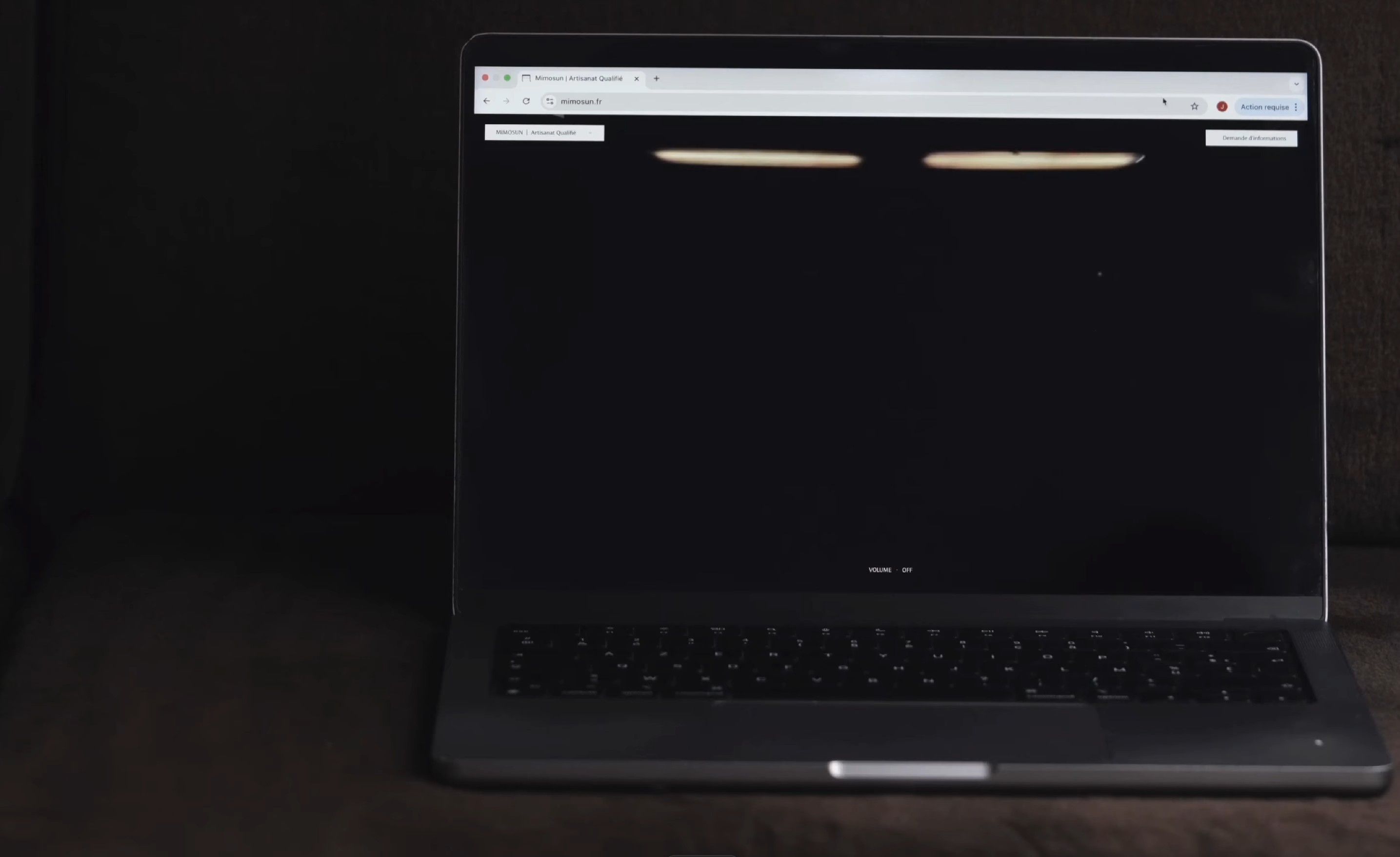 The same laptop in low light, the Mimosun homepage at its dark loading state — a near-black page with two faint horizontal streaks of warm light at the top.