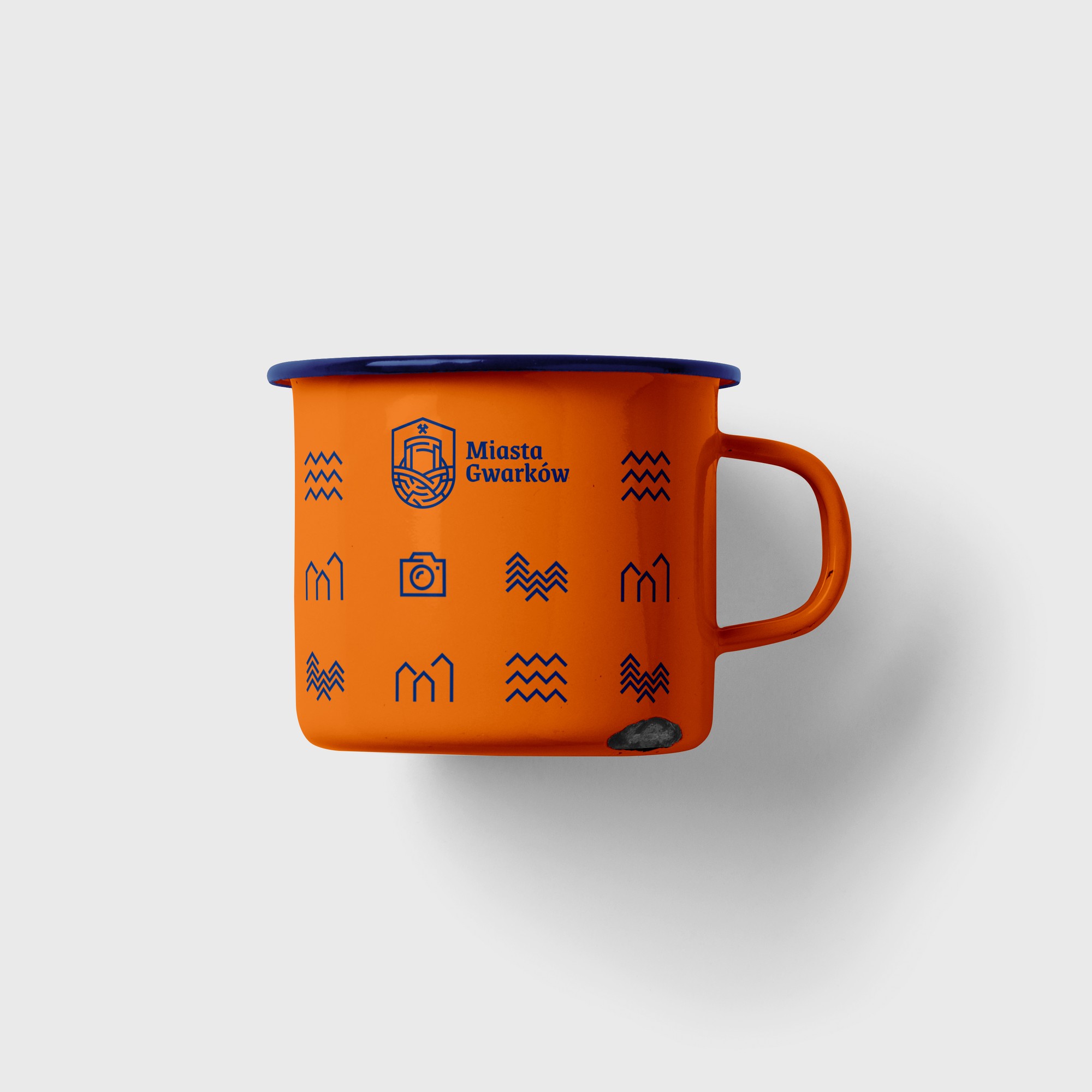 An orange enamel mug with a navy rim and pictograms