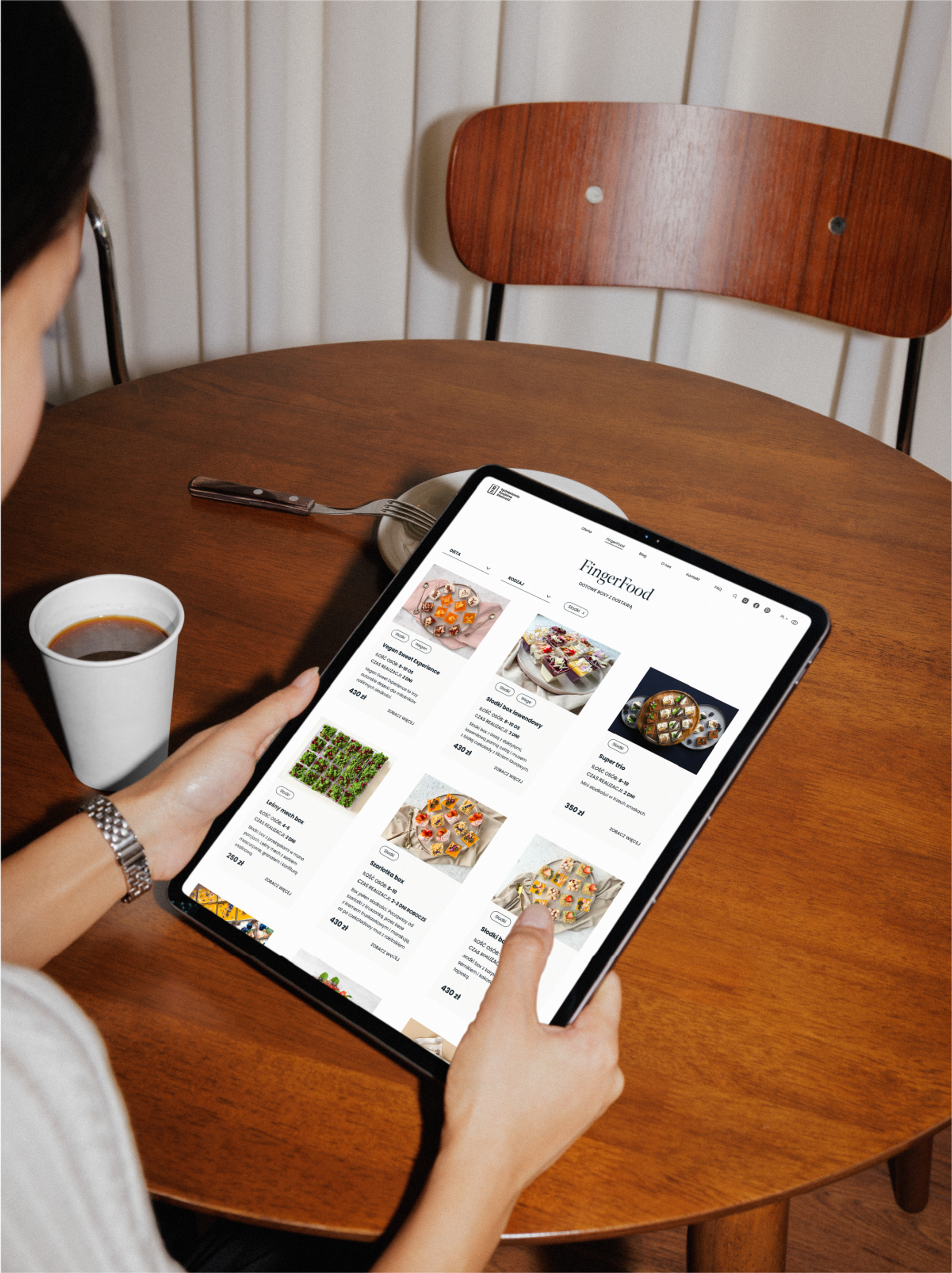 A woman holding an iPad with the finger food page of Catering Równość