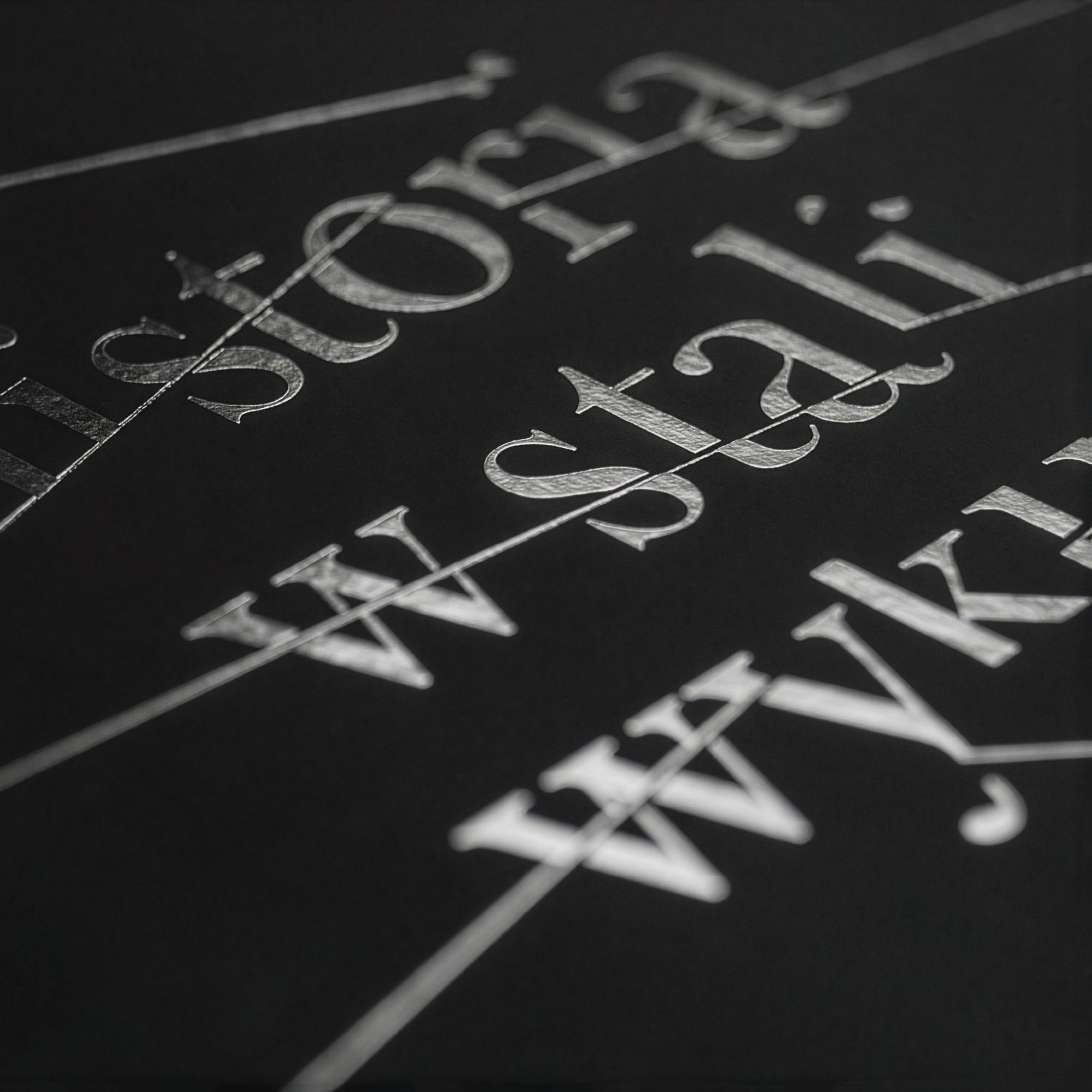 A close-up of silver letters crossed by thin lines on the black cover