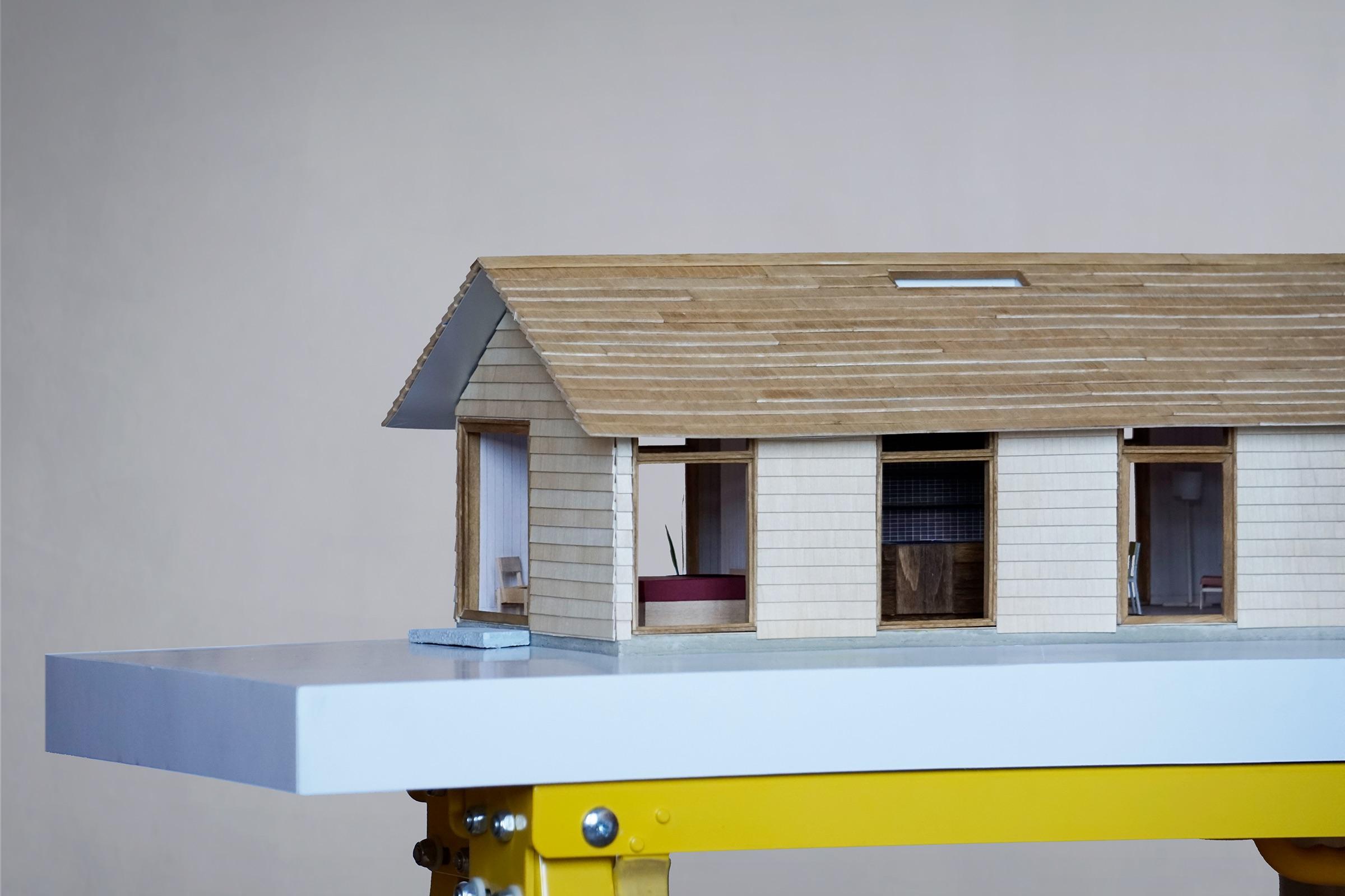 Model of a timber house on a yellow trestle
