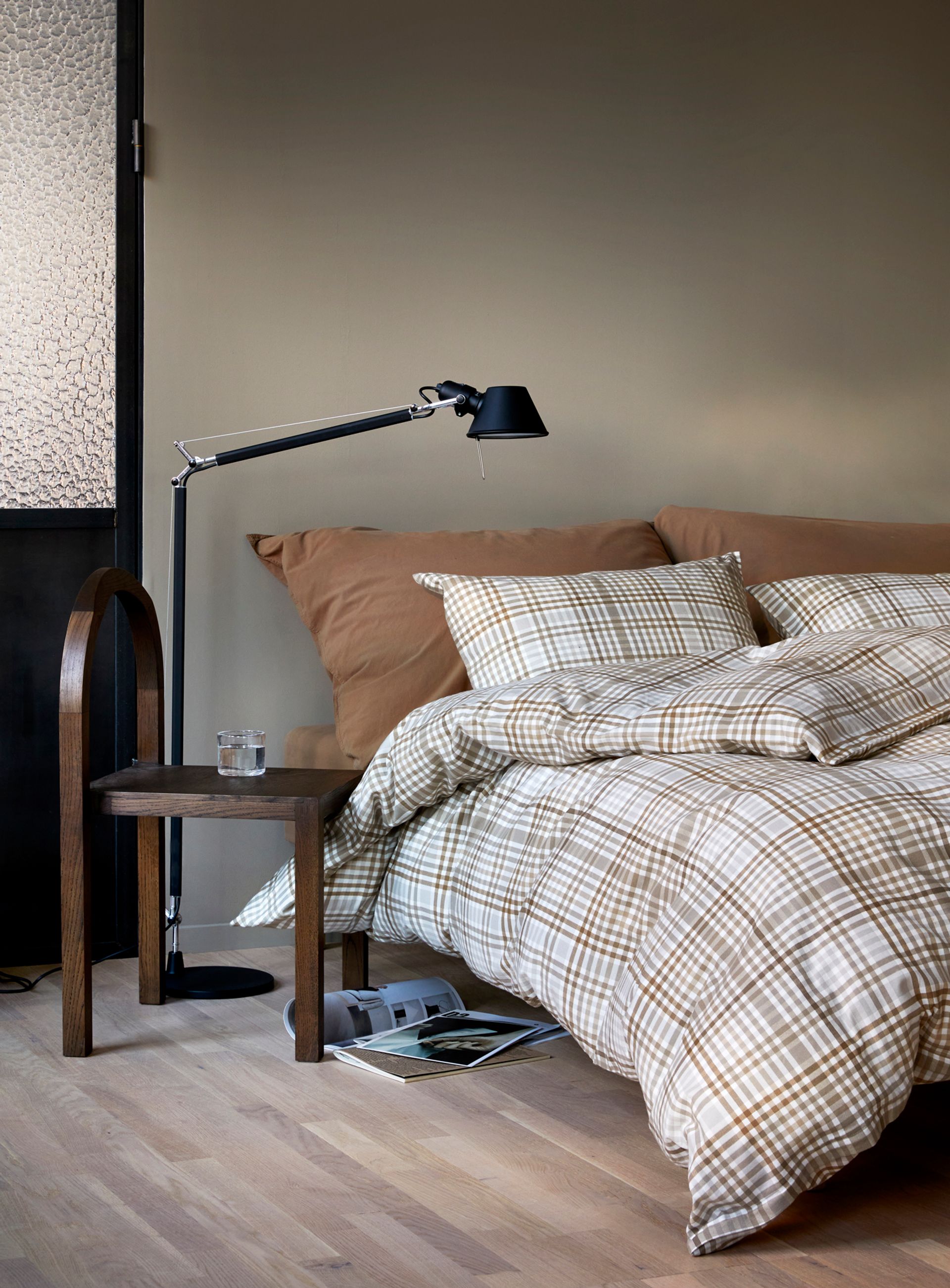 Nærbilde av oppredd seng med Høie Tor og Frøya sengesett i beige – en avslappet miks av smale striper og ensfarget bomull, som skaper en rolig og lun atmosfære på soverommet.