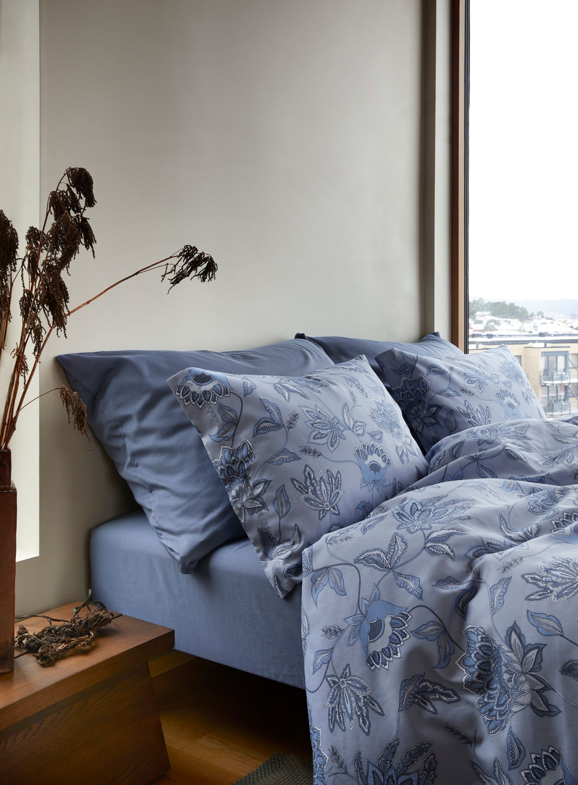 Oppredd seng med Høie Ragna sengesett i dempet lime – blomstrende mønster i duse grønntoner på hvit bunn, kombinert med ensfargede Frøya putetrekk for et friskt, men harmonisk uttrykk i soverommet.