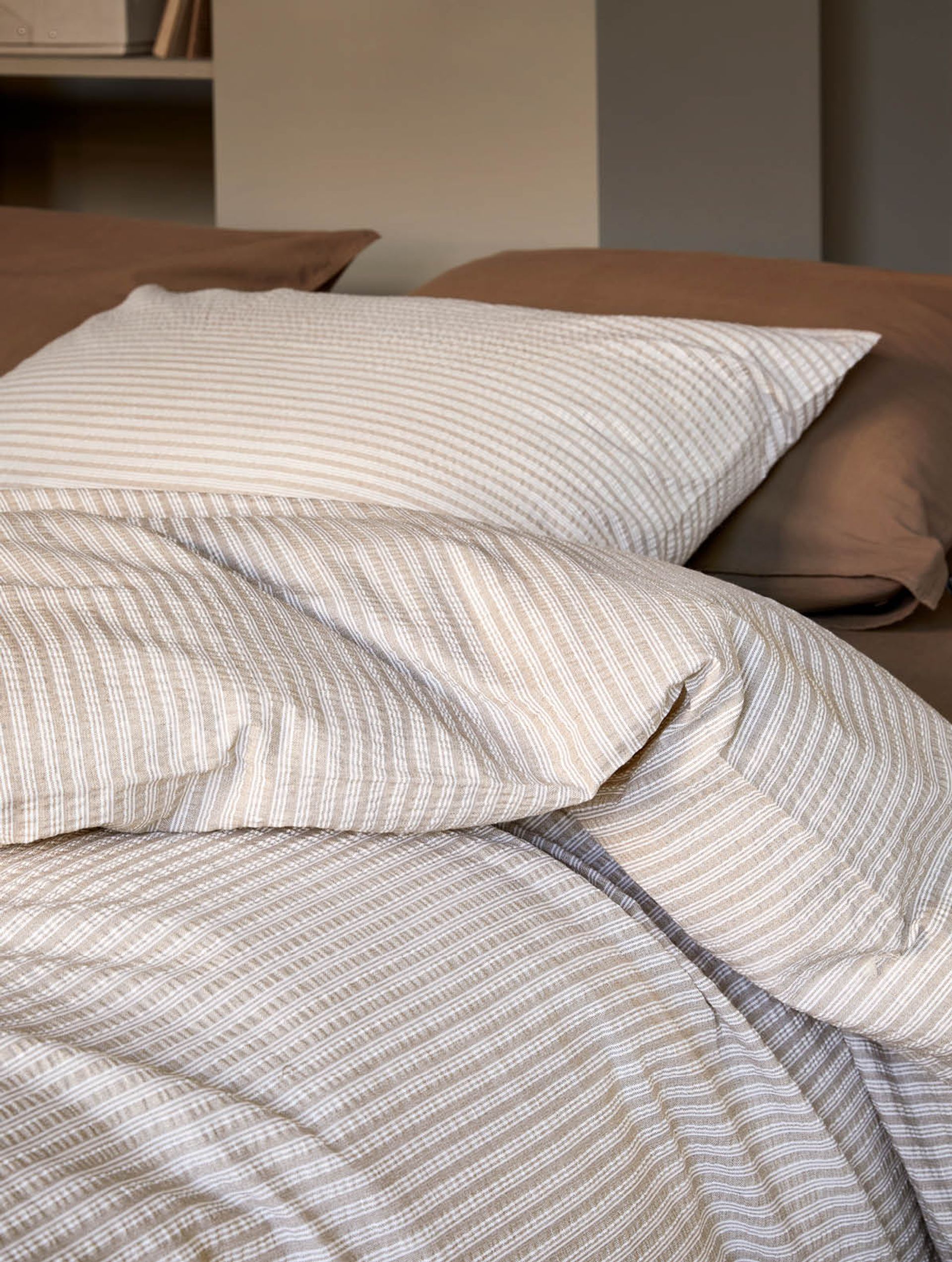 Nærbilde av mintgrønt kreppsengetøy med tydelig teksturert overflate. Dynen og puten har en luftig og myk struktur som gir en behagelig og sval følelse. Det enkle og moderne designet skaper et friskt og harmonisk uttrykk, ideelt for et avslappende soveromsmiljø.