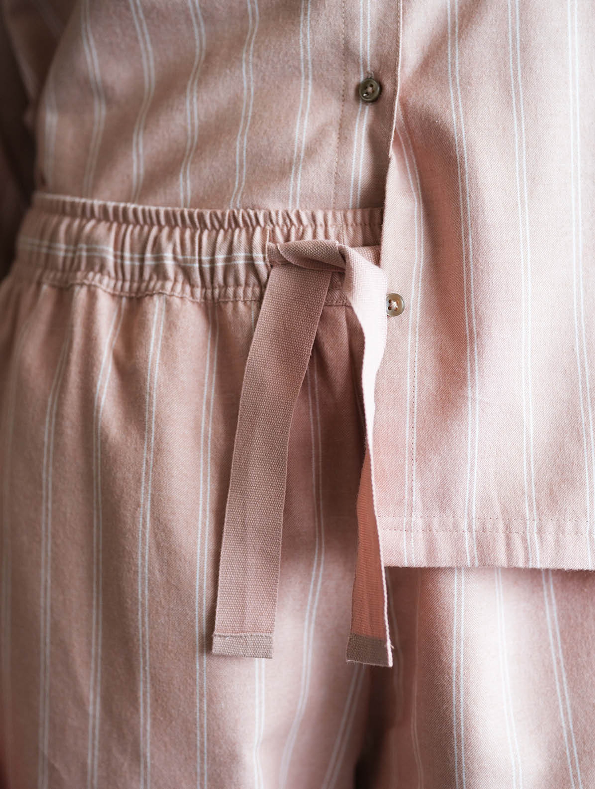 Detaljbilde av flanellpyjamas i varm rosa med klassisk stripemønster og justerbar snøring i livet – myk pysjamas i flanell for dame med komfortabel passform.