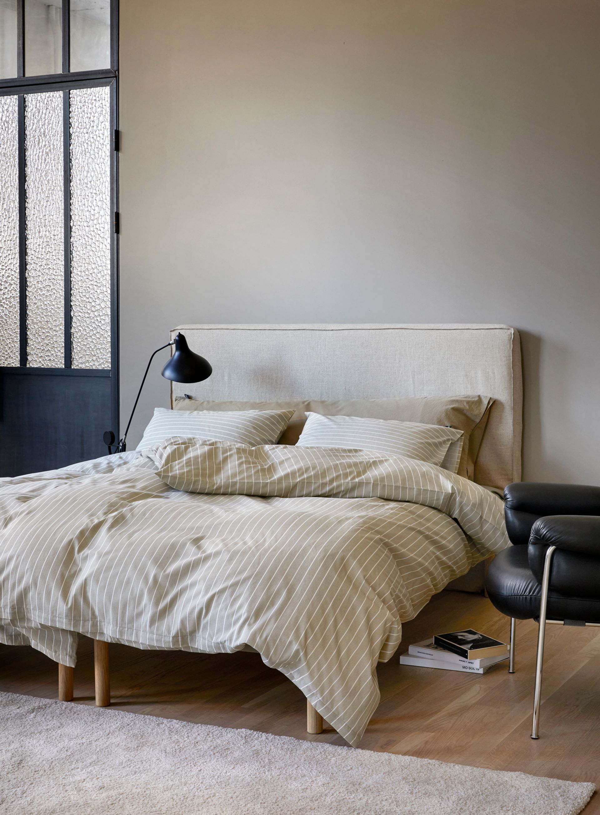 Oppredd seng med Høie Tor og Frøya sengesett i lyseblå nyanser – en kombinasjon av ensfarget og stripete bomullssateng, som gir et mykt og harmonisk uttrykk i et lyst soverom med naturlig dagslys.