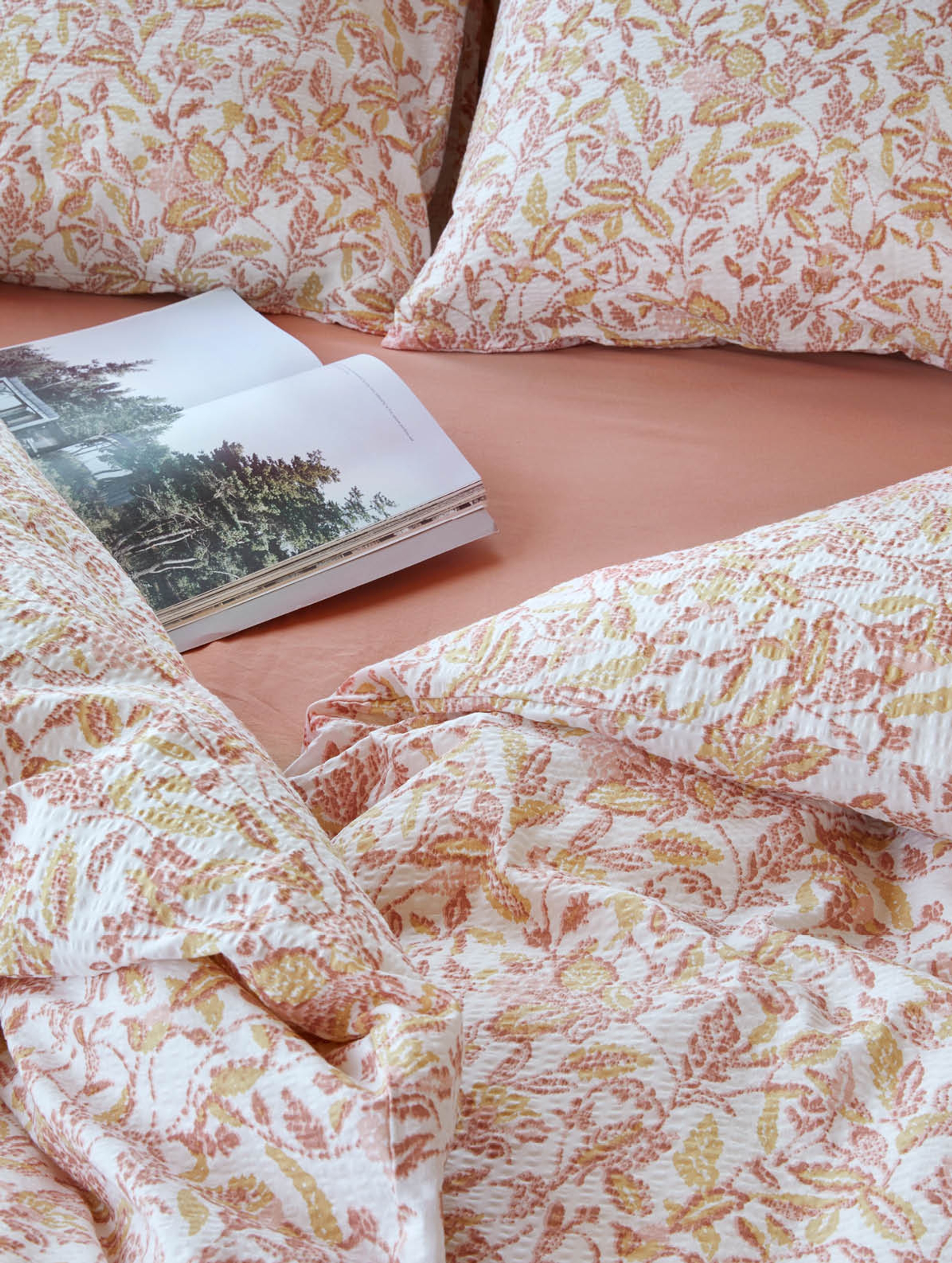 Nærbilde av seng med hvitt sengetøy dekorert med lyseblå horisontale striper. Sengetøyet har en teksturert overflate som gir det et lett og luftig utseende. Det enkle og tidløse designet skaper et rent og friskt uttrykk, perfekt for en rolig og avslappende atmosfære.