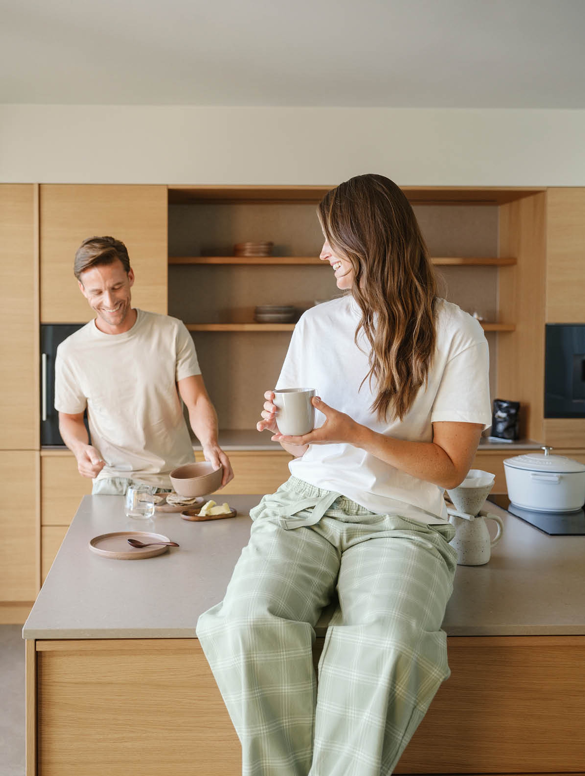 Par som nyter frokost hjemme iført komfortable flanellpyjamasbukser i dempet grønn rutemønster – myke pysjbukser i flanell for dame og herre til hverdagskomfort og rolige morgener.