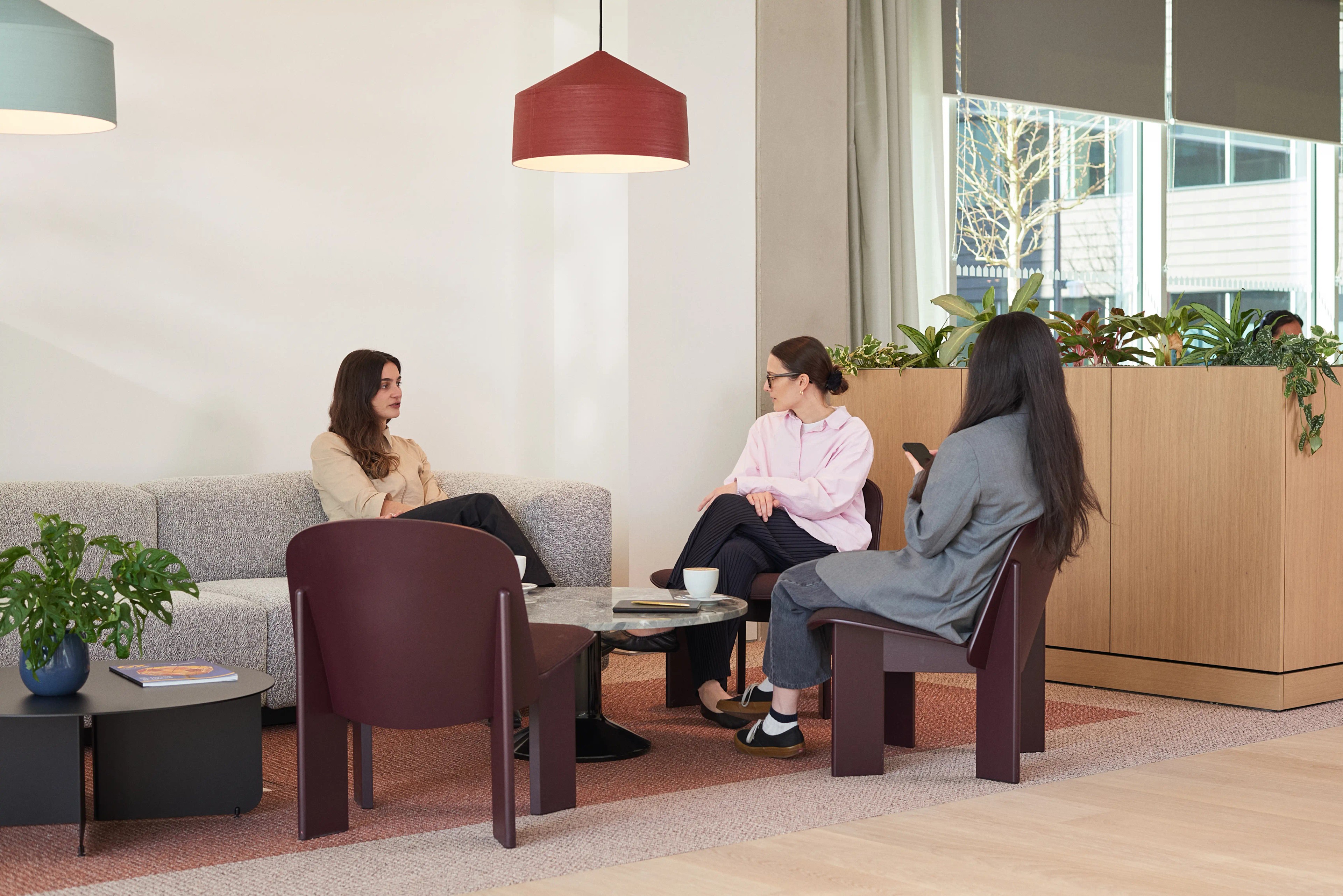Three women have a meeting in the Red Hall's communal seating area.