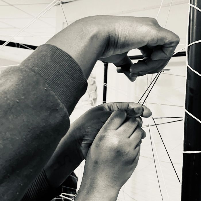 Des mains passent un fil dans la toile