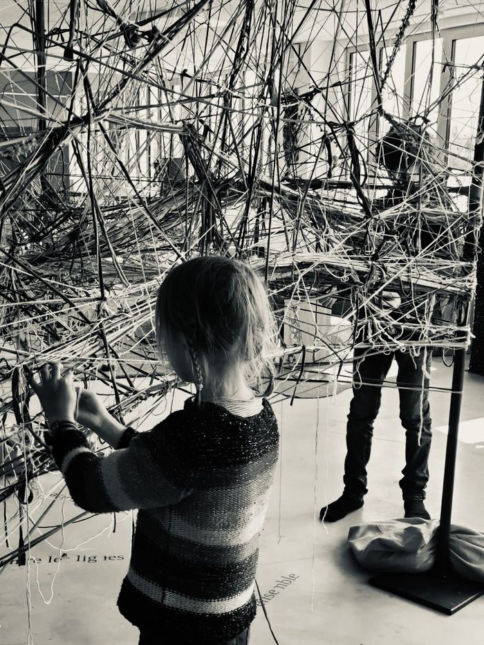 Une enfant tisse au milieu de la toile collective