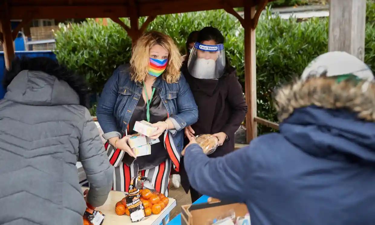 The headteacher of Mora primary school and another volunteer in masks handing out meals to parents at the school in Cricklewood, north London