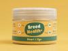 A jar of "Breed Health+" Heart & Eye supplement for pets against a mustard yellow background.