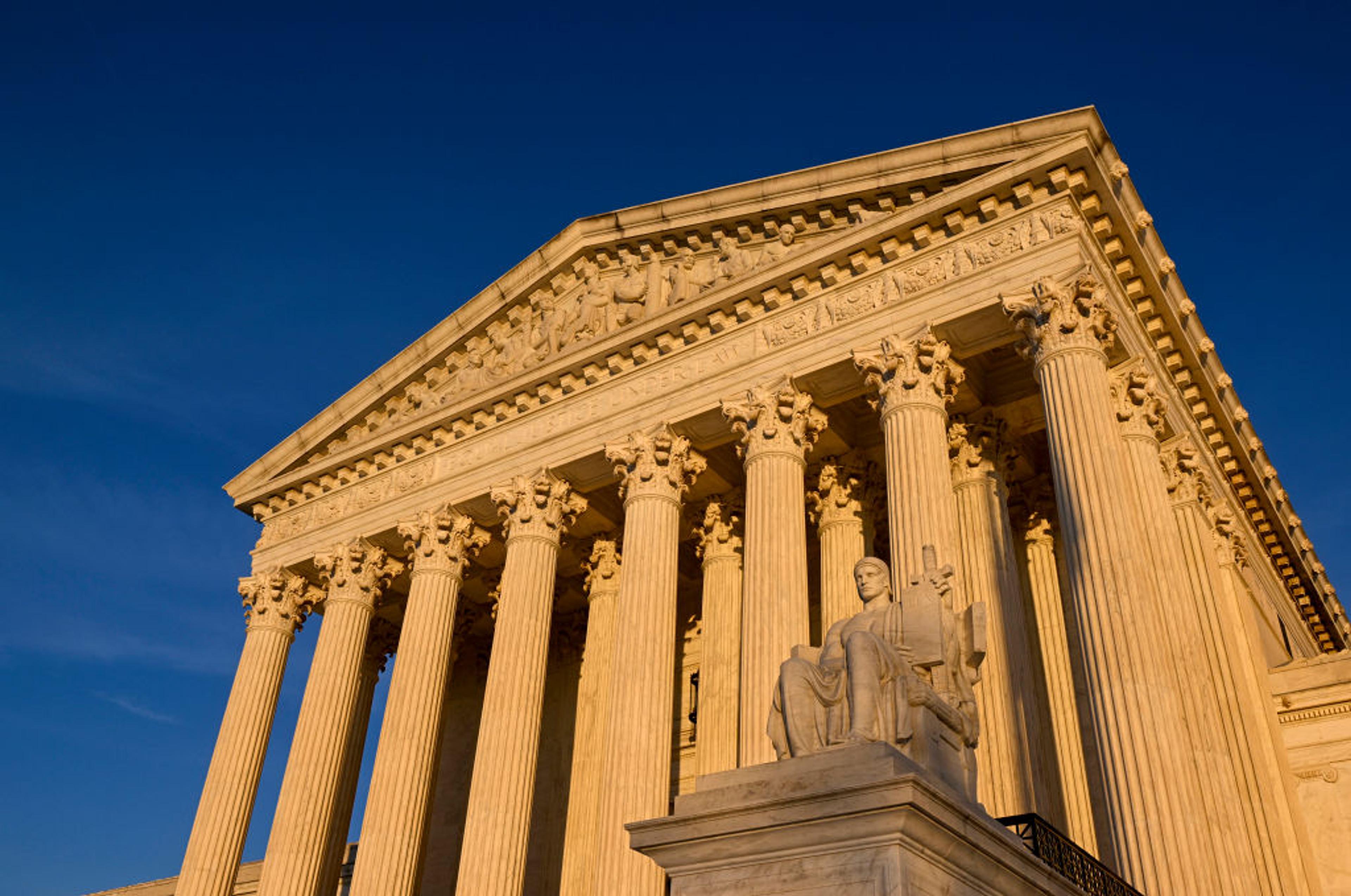 The statue, Authority of Law, by American sculptor James Earle Fraser outside the Supreme Court of the United States. The High Court building was built during the Great Depression and completed in 1935. Architect Cass Gilbert's design is based on a Greco-Roman temple.