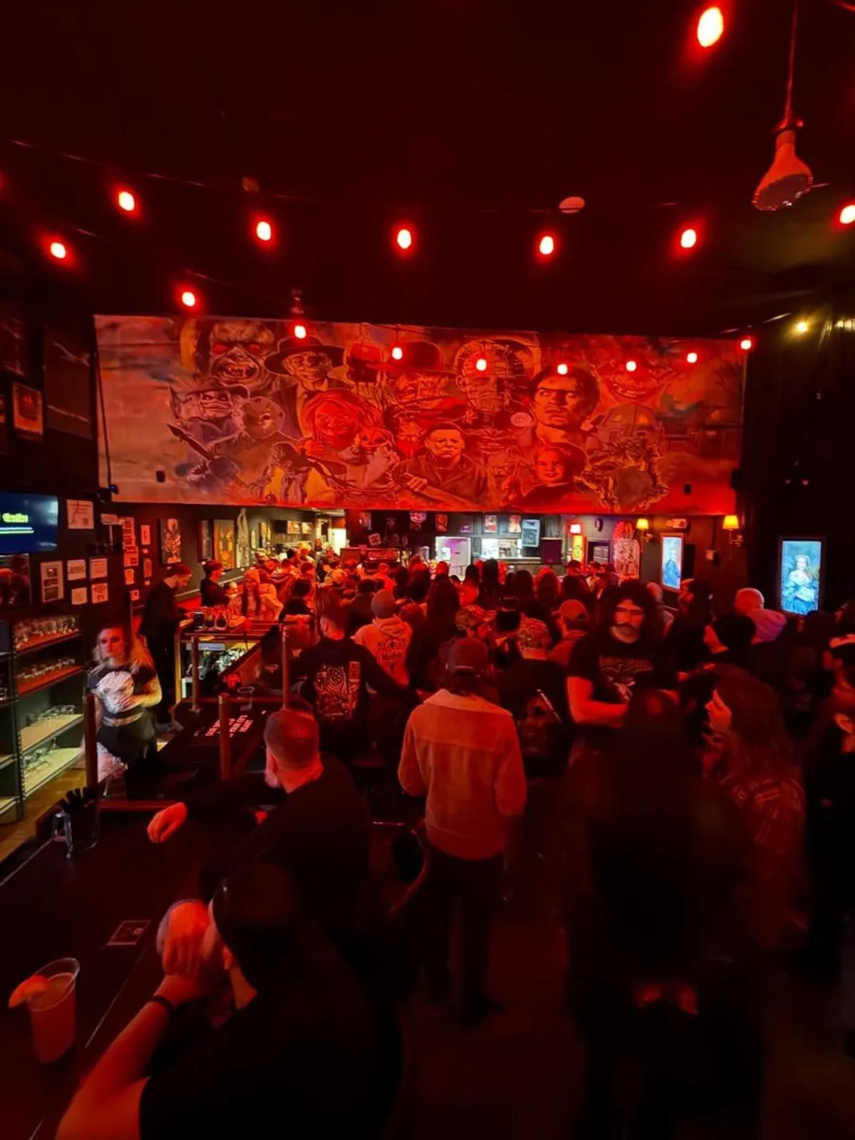 Packed crowd at The Pale Horse with red lighting and horror mural