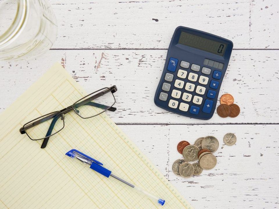 Calculator, glasses and financial papers on a desk