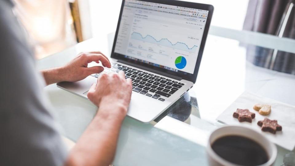 Hands on a laptop showing analytics charts