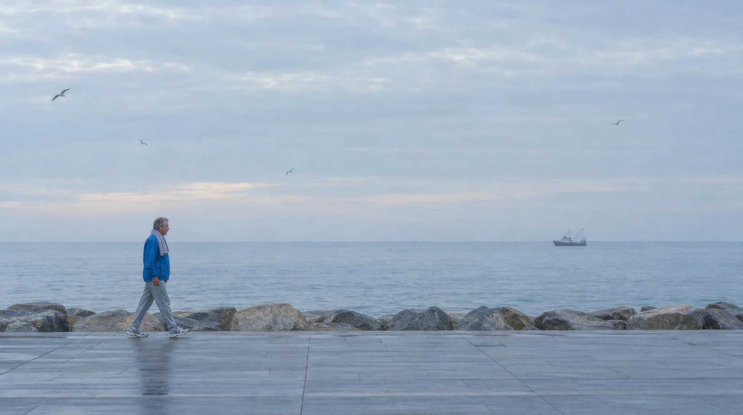 Hombre mayor caminando por el paseo marítimo de Barcelona al amanecer