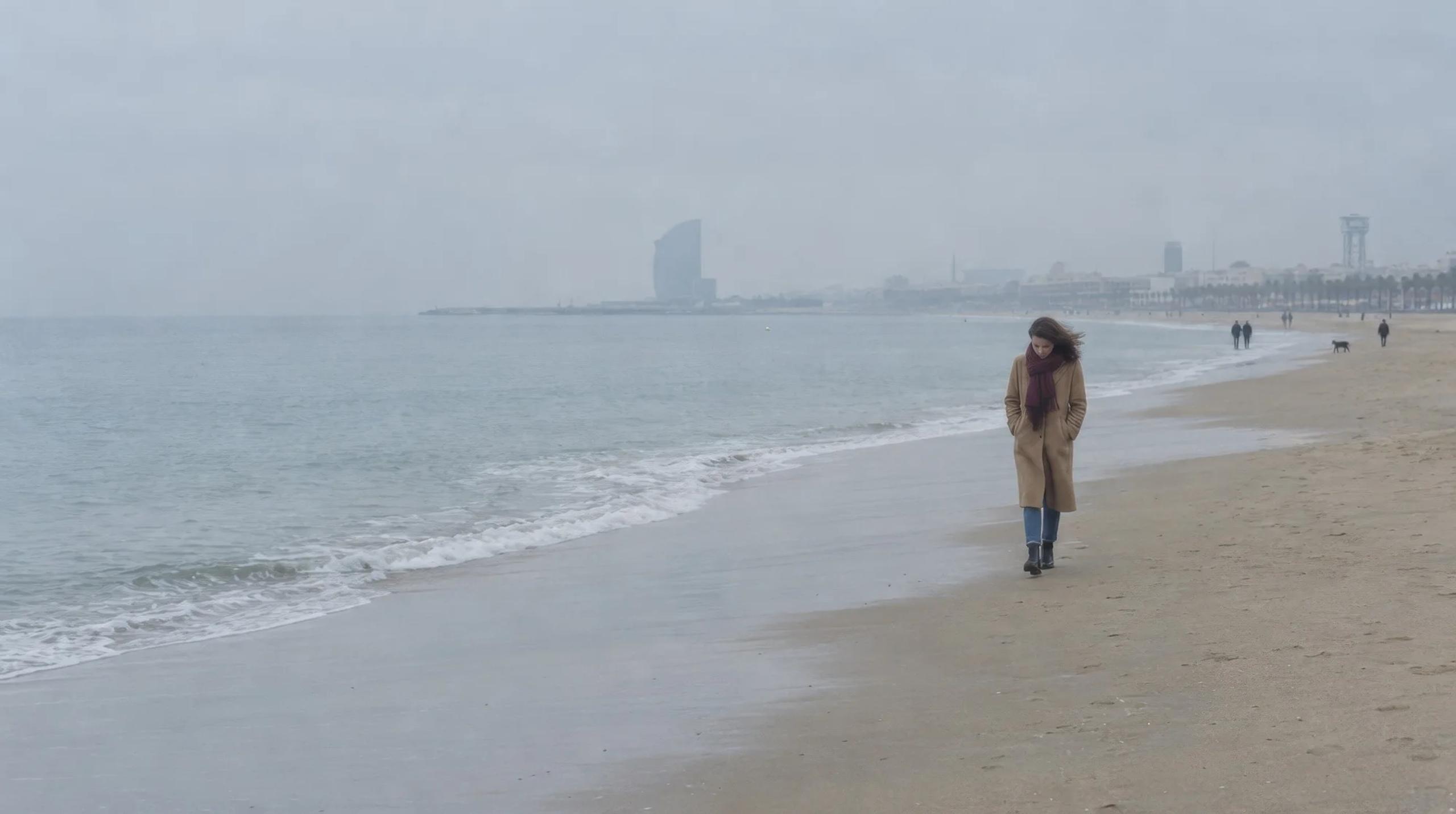 Mujer paseando sola por la playa de la Barceloneta un día gris de invierno