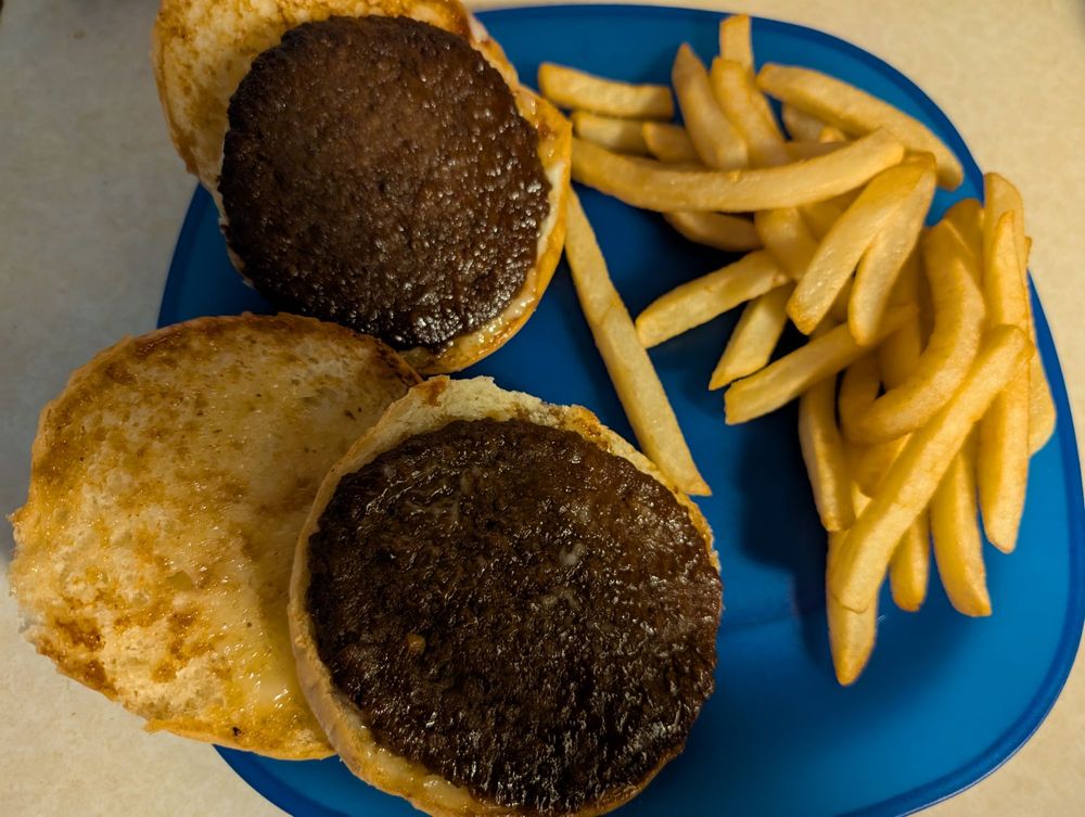 Two open-faced BBQ burgers on toasted buns with a side of fries on a blue plate