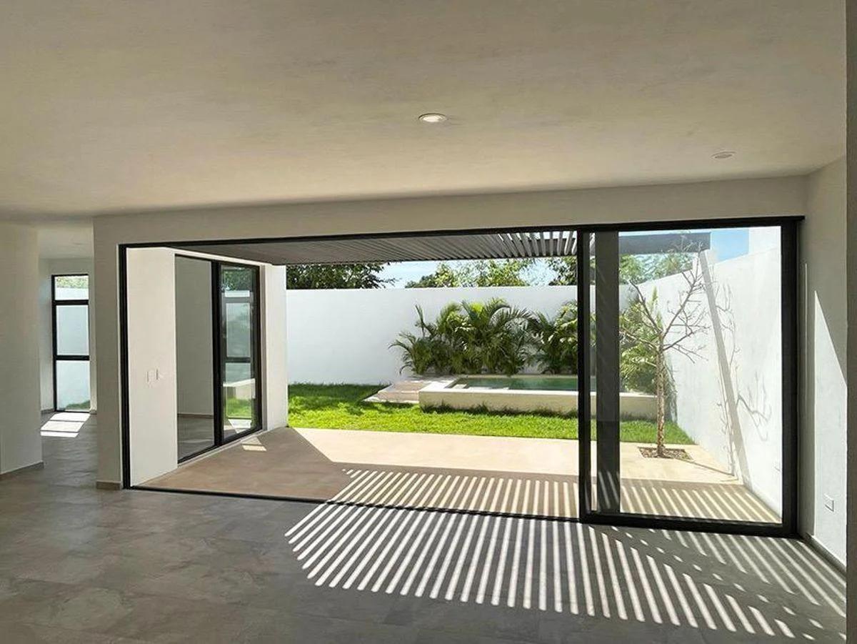 Grandes puertas de vidrio que se abren a un jardín privado y una piscina. La propiedad ofrece un diseño moderno con interiores espaciosos, ideal para vivir en familia. 