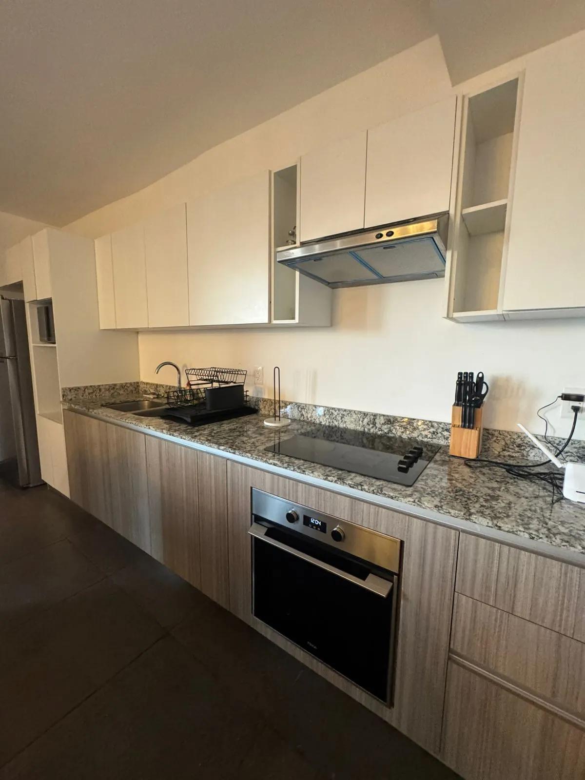 cocina Cocina moderna cuenta con gabinetes superiores blancos y gabinetes inferiores con vetas de madera. Tiene encimeras de granito o cuarzo,