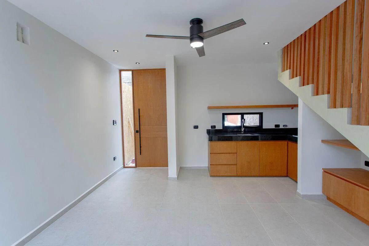 Sala de estar y la cocina de planta abierta de una casa adosada. Diseño moderno con baldosas de colores claros y paredes blancas.