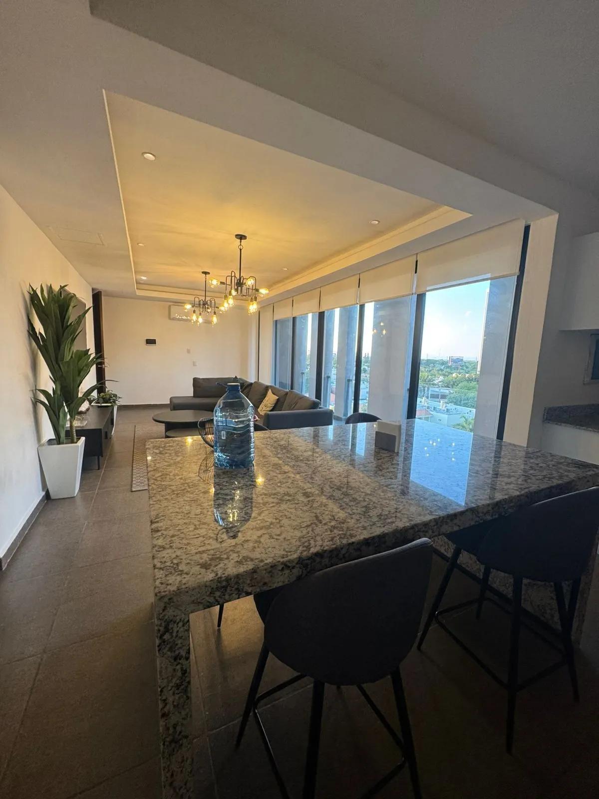 Sala de estar moderna con una decoración contemporánea, que incluye un sofá seccional gris oscuro, mesas de centro redondas nido y candelabros de estilo industrial. 