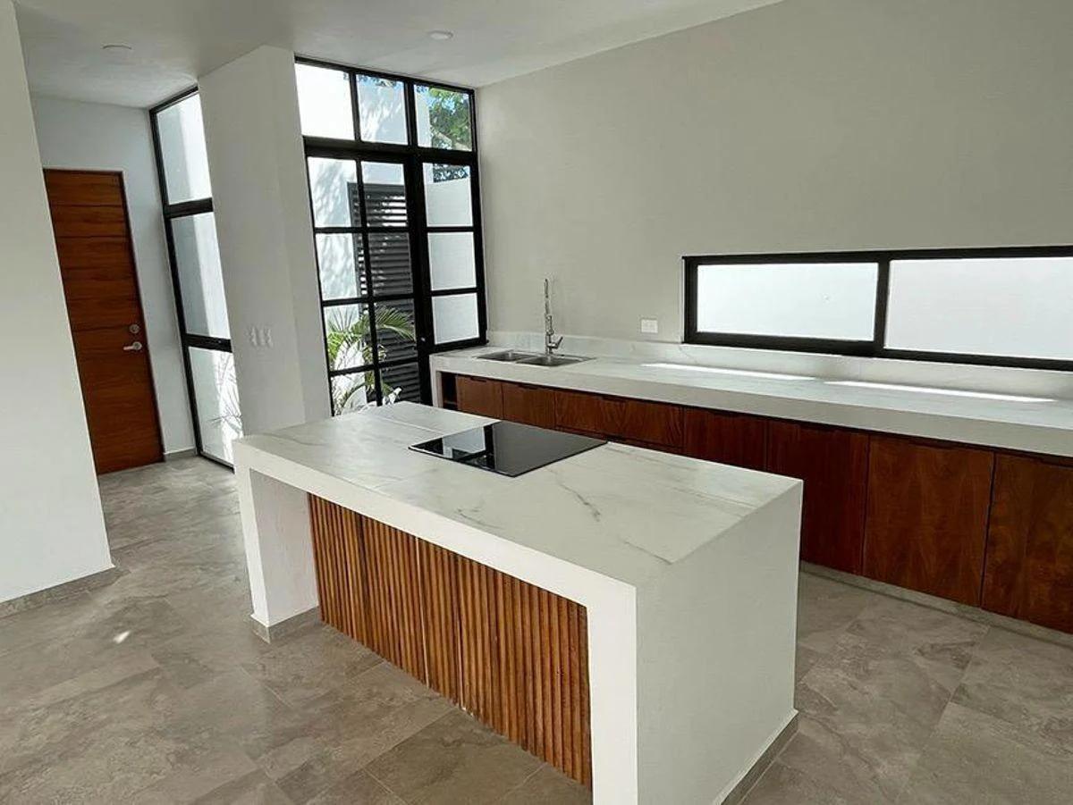Cocina moderna en una casa en venta ubicada en Dzityá, Mérida. Cuenta con acabados modernos de alta calidad, que incluyen una encimera con apariencia de mármol blanco y gabinetes de madera noble. 