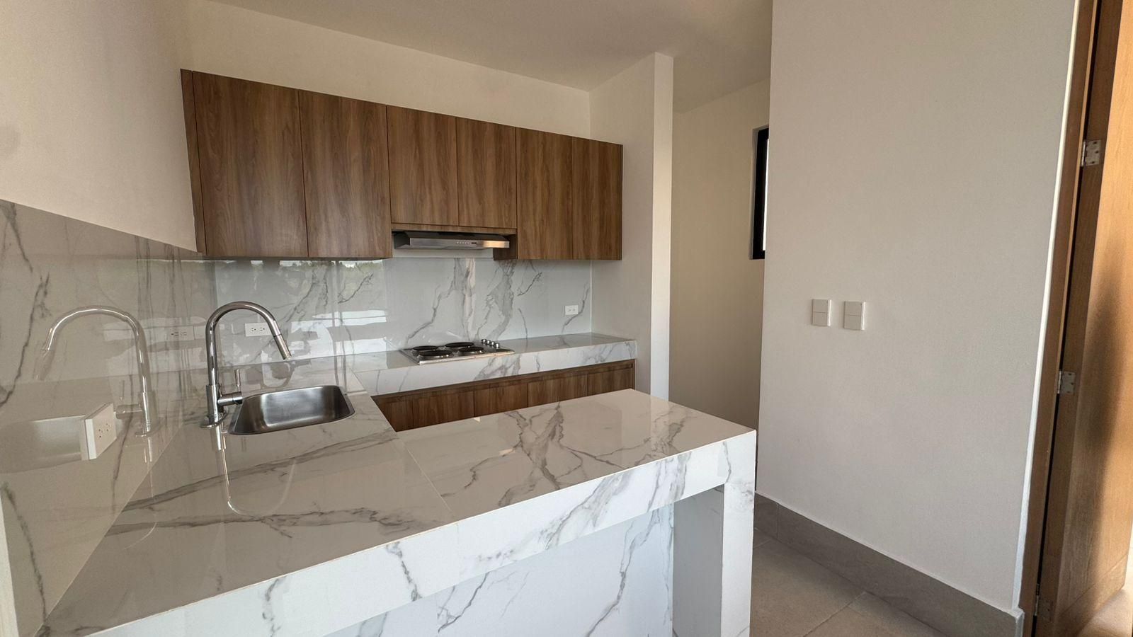 Cocina de un moderno departamento. Cuenta con una encimera de mármol blanco.