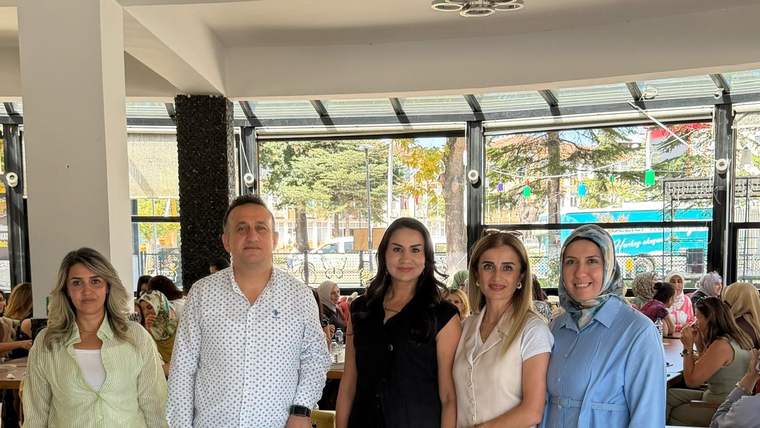 İç mekânda, kafe masaları arasında yan yana duran üç kadın ve iki erkekten oluşan beş kişilik grup.