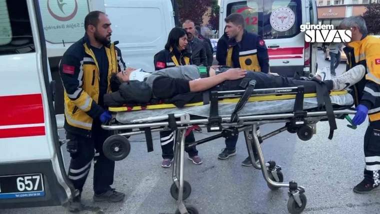 Sarı yelekli sağlık görevlileri, sedyede yatan bir kişiyi ambulansın yanında taşıyor.