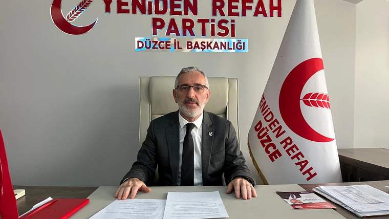 Yeniden Refah Partisi Düzce İl Başkanlığı yazılı odada, masasında oturan bir kişi ve parti bayrağı görülüyor.