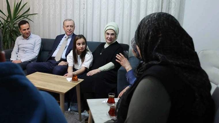Bir odada oturan üç yetişkin ve bir çocuk, karşılarındaki başörtülü kadınla sohbet ederken görülüyor.