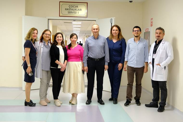 Çocuk hastalıkları servisi önünde bir grup sağlık çalışanı poz veriyor.