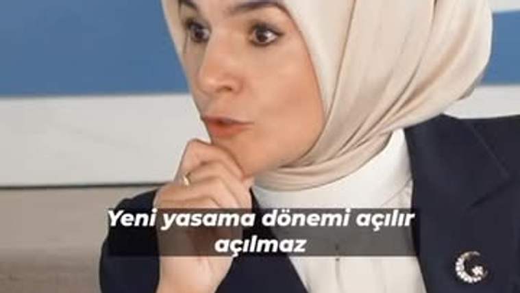 Başında başörtüsü olan bir kadın, elini çenesine dayamış, konuşuyor.