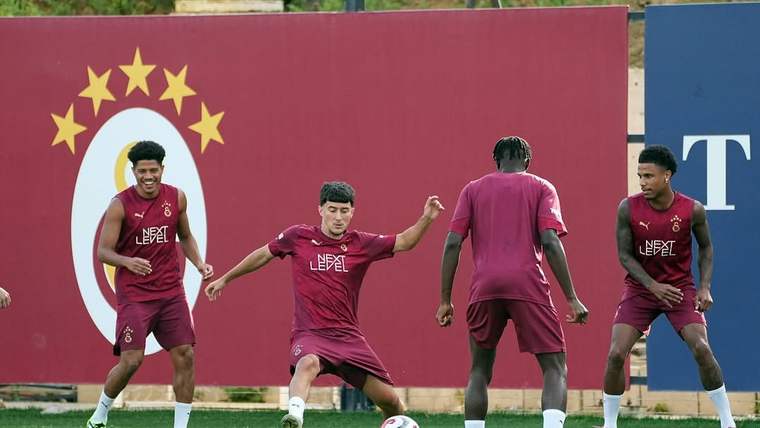 Antrenman sahasında bordo formalar giyen futbolcular, top çalışması yaparken görülüyor.