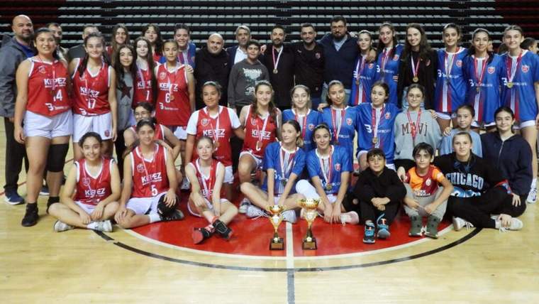 Basketbol takımı, madalyalar ve kupalarla birlikte poz veriyor.