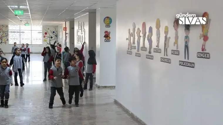 Koridorda yürüyen öğrenciler, duvarda çeşitli meslekleri temsil eden karakterlerin resimleriyle karşılaşıyor.