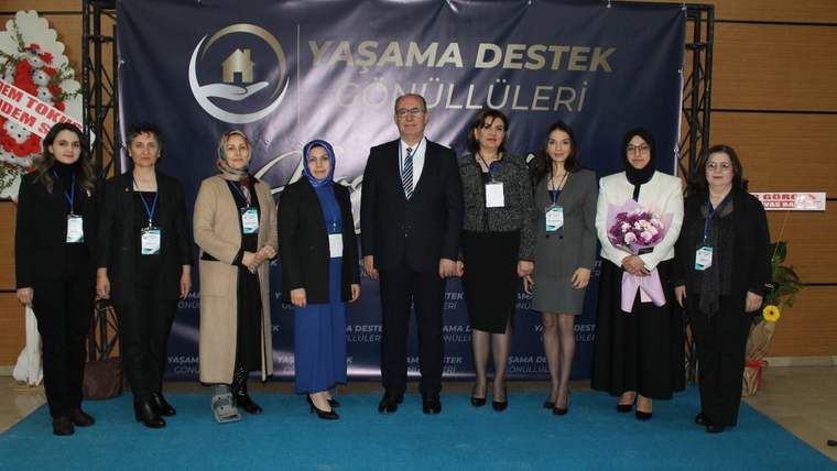 Üzerinde “Yaşama Destek Gönüllüleri” yazan pankart önünde, dokuz kişi yan yana duruyor.