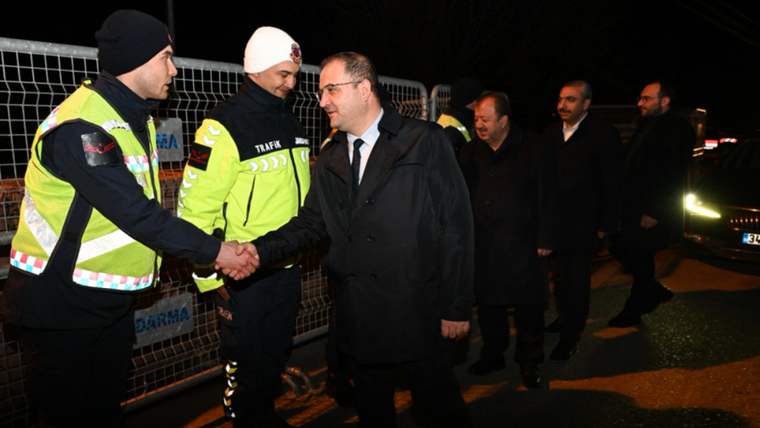 Görev başında olan trafik polisleriyle el sıkışan bir kişi, arka planda başka kişiler duruyor.