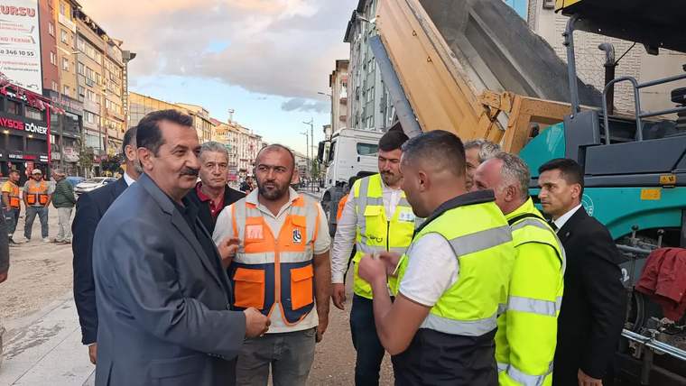 Bir grup insan, inşaat alanında toplanmış, işçiler ve yöneticiler arasında konuşma yapılıyor.