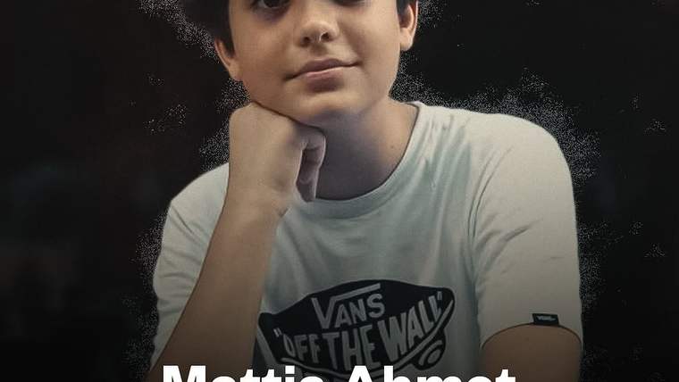 Koyu arka plan önünde beyaz Vans tişörtü giyen bir çocuk, başını eline dayamış; altta “Mattia Ahmet” yazıyor.