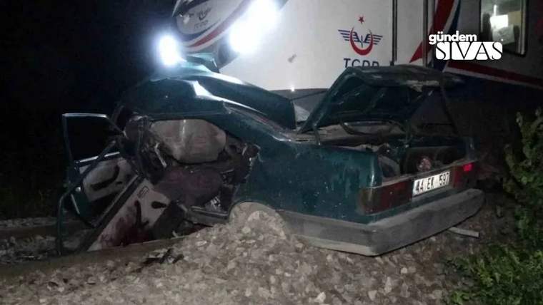 Demiryolu üzerinde devrilmiş bir otomobil, arka kapısı açık ve içi görünür durumda.