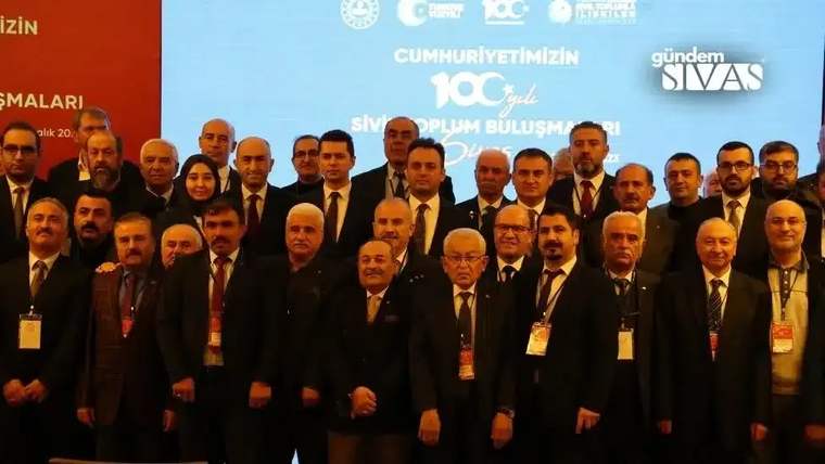Sivil toplum buluşmasında bir grup insan, sahnede poz veriyor.