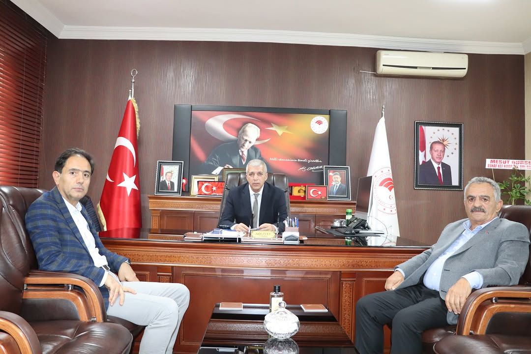 Sivas Tarım ve Orman İl Müdürlüğü'nde üç kişi, masanın etrafında oturuyor; arka planda Türk bayrağı ve çeşitli portreler var.