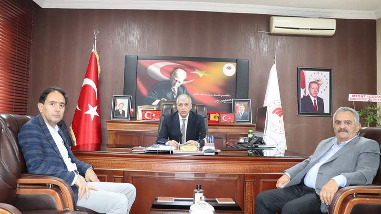 Sivas Tarım ve Orman İl Müdürlüğü'nde üç kişi, masanın etrafında oturuyor; arka planda Türk bayrağı ve çeşitli portreler var.