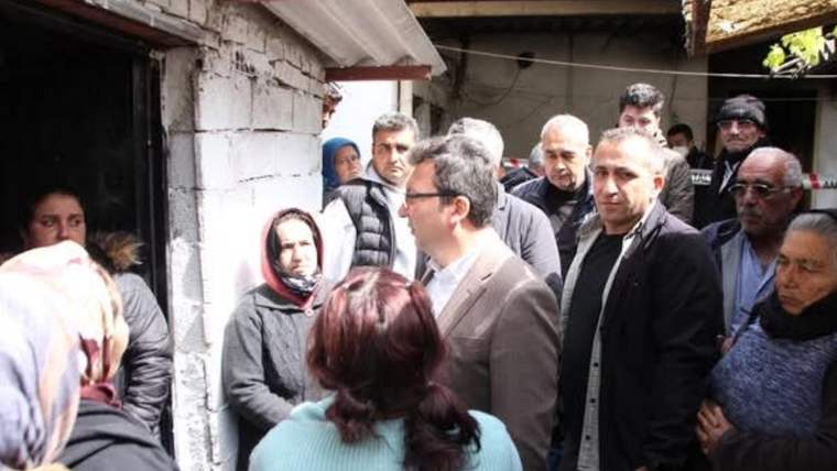 Bir grup insan, bir evin önünde toplanmış, bir kişi konuşuyor.
