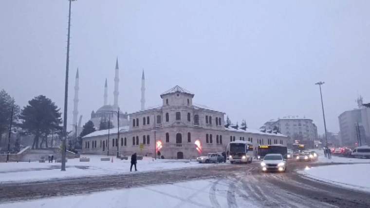 Karla kaplı bir cadde üzerinde, tarihi bir bina ve cami görünmektedir.