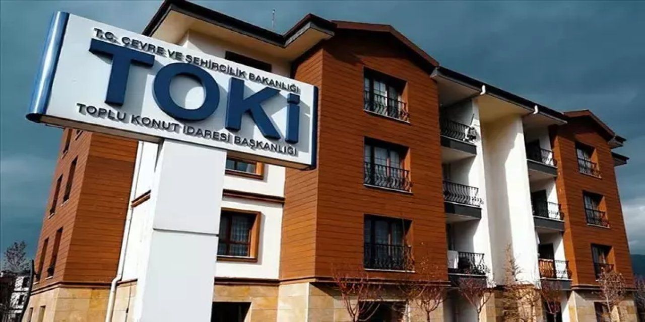 Önünde TOKİ ve Toplu Konut İdaresi Başkanlığı yazılı tabela bulunan çok katlı konut binaları.